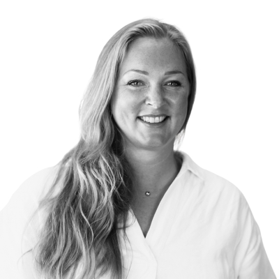 Porträttfoto i svartvitt av Linda Brorson Edh, regionchef. En kvinna med långt ljust hår och vit skjorta, som ler varmt mot kameran.